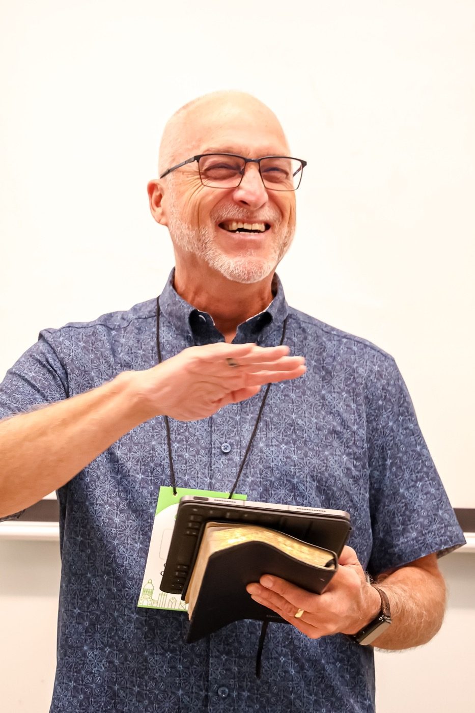 A speaker smiling and teaching while holding a book