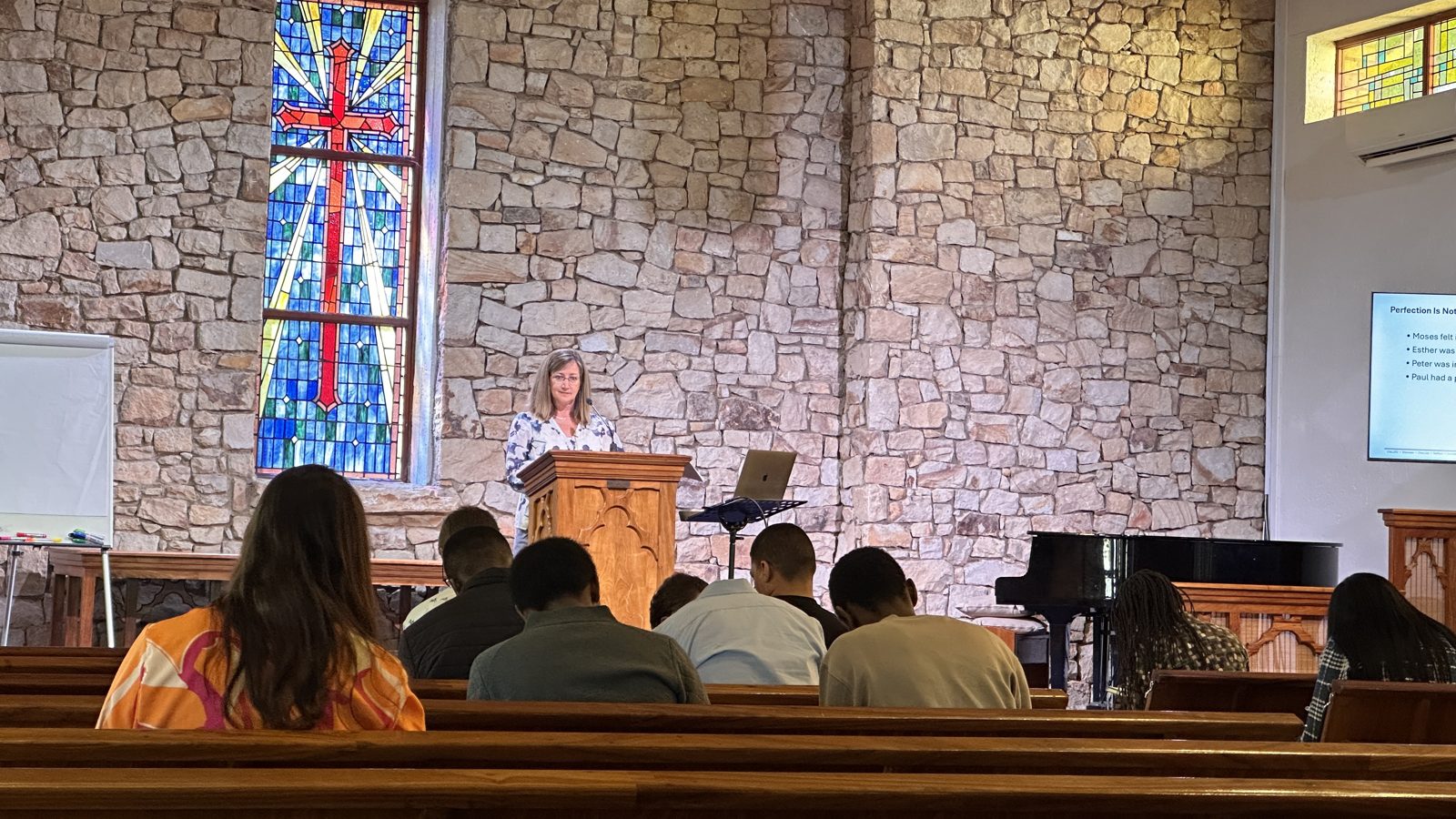 A gathering inside a church with a stained glass cross